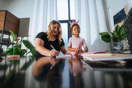 Mother and child daughter draws creatively at home at the table