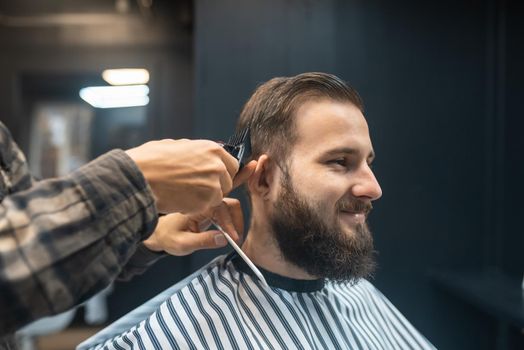 Men's hairstyling and haircutting with hair clipper in a barber shop or hair salon