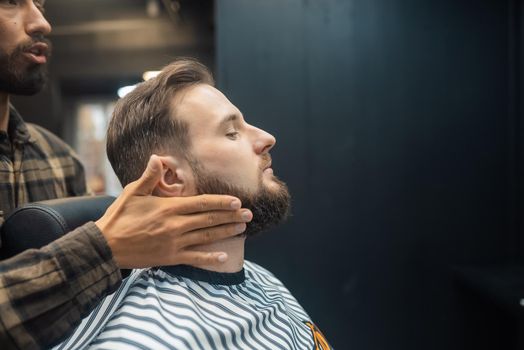 Facial applying lotion after shave in Barber shop. Master hands close up