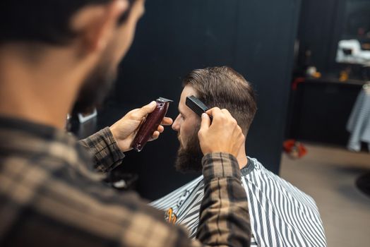 Men's hairstyling and haircutting with hair clipper in a barber shop or hair salon