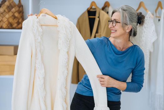 Elderly woman during chooses white sweater