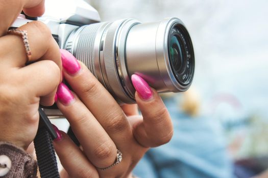 Close-up of a digital camera being used by a woman with painted fingernails