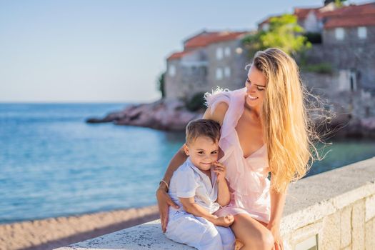 Mother and son tourists on background of beautiful view St. Stephen island, Sveti Stefan on the Budva Riviera, Budva, Montenegro. Travel to Montenegro concept.