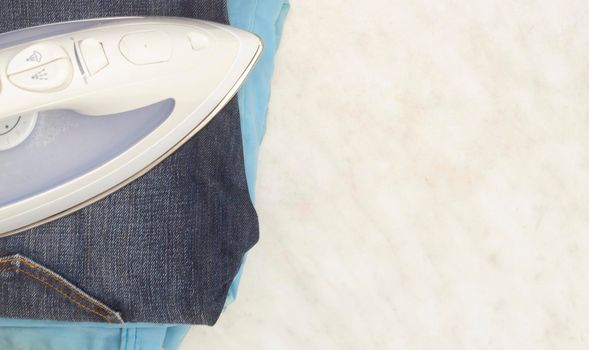 Steam iron, classic jeans and summer jeans on a light background, copy space