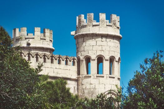 White stone turrets of a medieval castle against a clear blue sky background