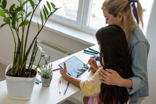 Back to school. Happy child and adult are sitting at desk. Girl doing homework or online education.