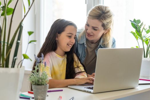 Friendship of mom and her cute little daughter. They wallow at home in casual clothes and shopping online together using a laptop. They buy new toys for pretty little girl.