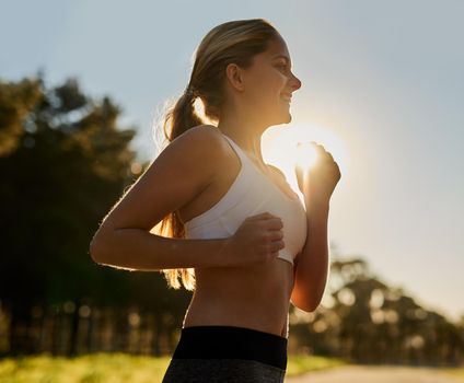 Shot of a happy young woman out for a run in nature.