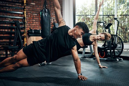 Shot of two sporty young people working out together at the gym.