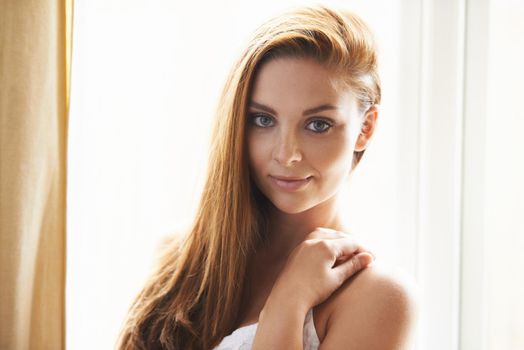 Portrait of a young woman standing in front of a window.