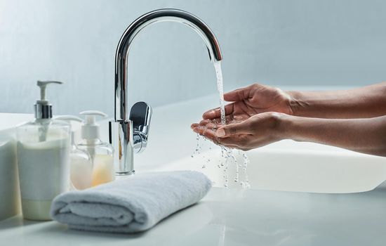 Cropped shot of a man washing his hands in a bathroom sink.