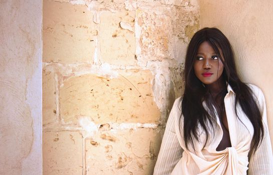 Beautiful young African woman looking to the side standing against a wall