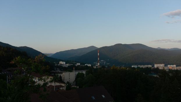 LAZAREVSKOE, SOCHI, RUSSIA - MAY, 27, 2021: Panorama of sunset in the mountains. A magical view of the sea and small town from the observation deck.