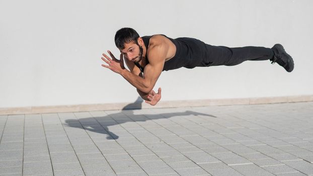 A man in black sportswear jumps while doing push-ups outdoors