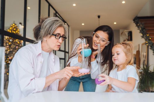 Family doing chemical experiment, mixing flasks indoors, close view.