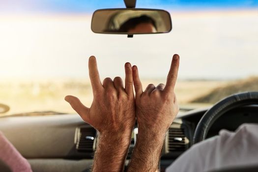 Shot of two unrecognizable men putting their hands together to make a hand sign while driving in a vehicle.