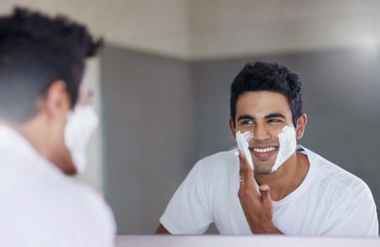 Shot of a handsome young man shaving his facial hair in the bathroom.