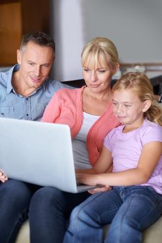 A family of three using a laptop in the lounge.
