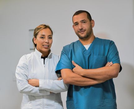 Shot of two confident young dentists standing with arms folded while looking into the camera inside the office.