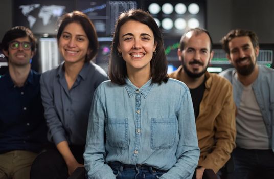 Group photo of stock traders teams in the office looking at camera. Focus on woman in the middle. Teamwork concept.