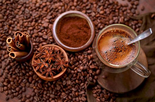 Tasty steaming espresso in cup with coffee beans. View from above. Dark background.