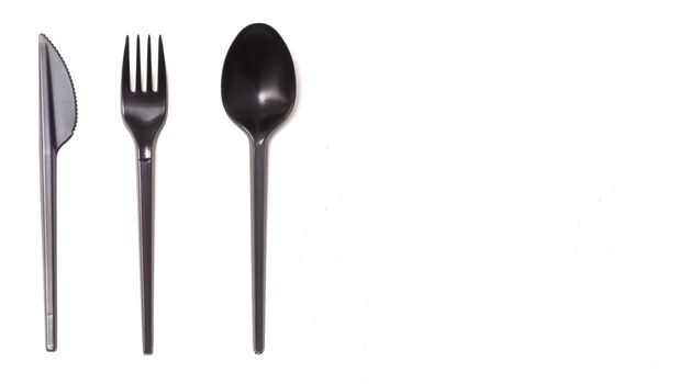 Repeating black plastic disposable knife,spoon on white background, copyspace.