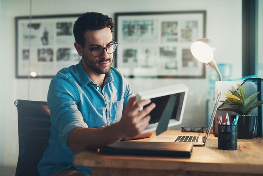 Shot of a young businessman looking at a photo frame while working in his office.