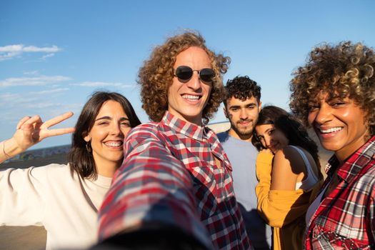 Group of multiracial friends take selfie having fun outdoors looking at camera. Friendship and social media concept.