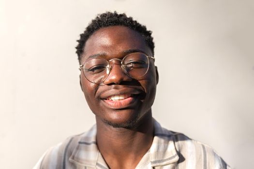 Headshot of young happy and smiling black man wearing glasses outdoors. Portrait.