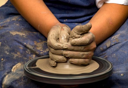 Potter modeling ceramic pot from clay on a potter's wheel.