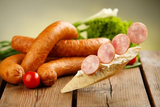 Polish kielbasa with vegetables and bread on wooden background