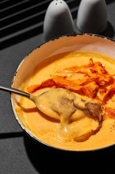 Close-up shot of a delicious cream soup with meat served on a black table, top view. Gourmet meal, restaurant serving. Cooking concept.