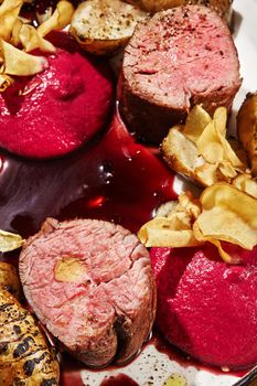 Macro photo of a gourmet roasted veal meat with jerusalem artichokes and sauce. Served on a white plate. Restaurant cooking concept.