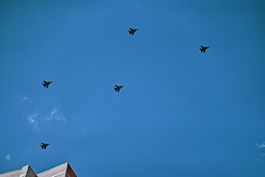 Parade of military aircraft over the city. Group of Russian army air force shows aerobatics in blue sky.