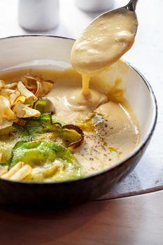 Close-up shot of a delicious cream soup with vegetables served on a wooden table, top view. Gourmet meal, restaurant serving. Cooking concept.