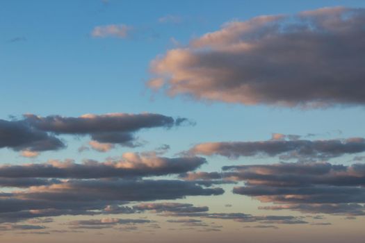 Fluffy flat clouds against a blue sky during golden hour