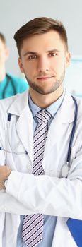 Two male medical workers in uniform at the workplace, close-up, vertical photo. Cooperation, team, clinic staff