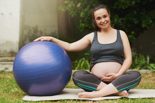 Full length portrait of an attractive young pregnant woman exercising outside.