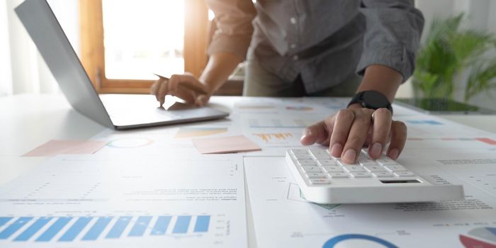 Close up businessman hand using calculator and working with laptop calculate about finance accounting at coffeeshop outdor.finance accounting concept.