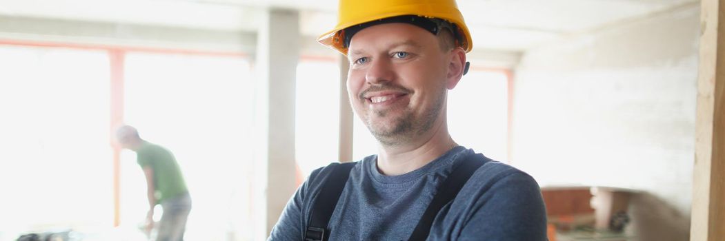 A man in a helmet is standing indoors, a construction worker. Renovation of premises, architecture, foreman