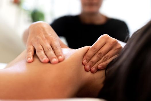 Close up of female hands giving back massage to woman. Selective focus. Physiotherapy and bodycare concept.