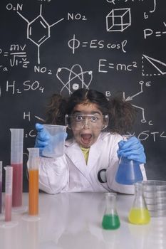 crazy scientist girl with gloves and goggles in lab coat with chemical flasks, blackboard background with science formulas, explosion in the laboratory, back to school concept, vertical photo