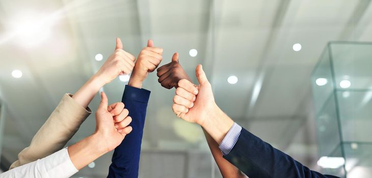 Shot of a group of hands showing thumbs up in an office.