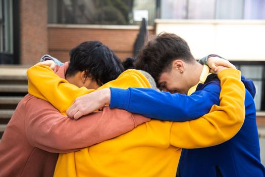 Diverse friends in group hug together concentrating before important event. Embracing in a circle to say motivational pep talk. Togetherness and teamwork concept.