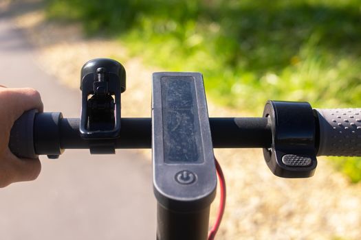 Electric scooter steering wheel on a green forest background close up