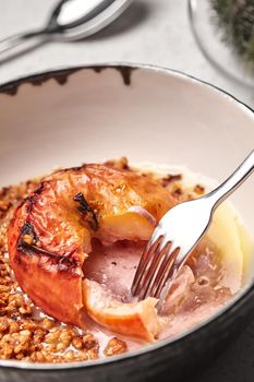 Close-up photo of a tasty baked apple stuffed with honey and nuts, healthy nutrition, delicious sweet food, gorgeous fruit dessert flavored with cinnamon. Autumn or winter dessert. Served in a deep bowl. Cooking concept.