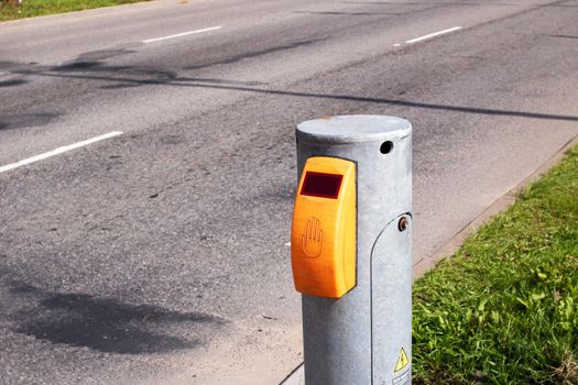 Yellow traffic light button on road background close up