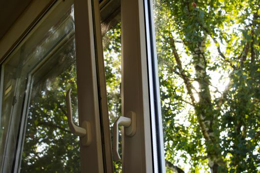 A slightly open window on a background of wood and sunlight