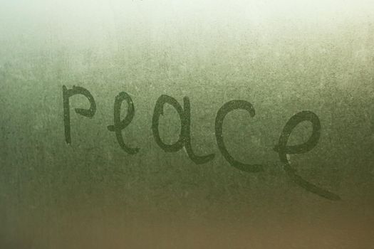 Inscription peace on a wet glass close up