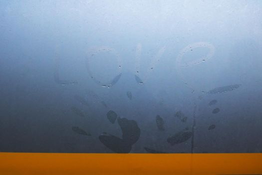 Palm print and inscription love on a wet glass close up